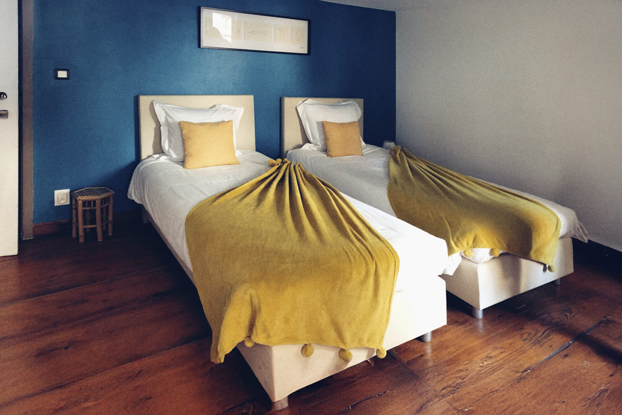 deux lits une place recouverts d'un plaid jaune dans une chambre cosy au mur bleu